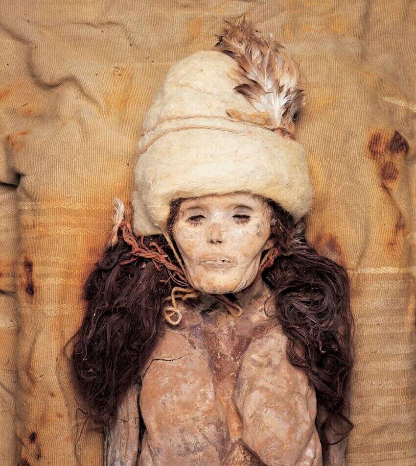 上图是一具木乃伊化的女性尸体，头戴白色毛皮帽子