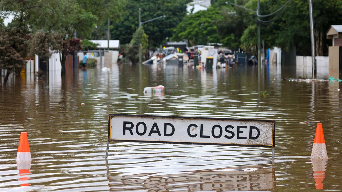 洪水恢复的概念，被洪水淹没的街道，道路关闭标志和锥可见，水涌到房屋